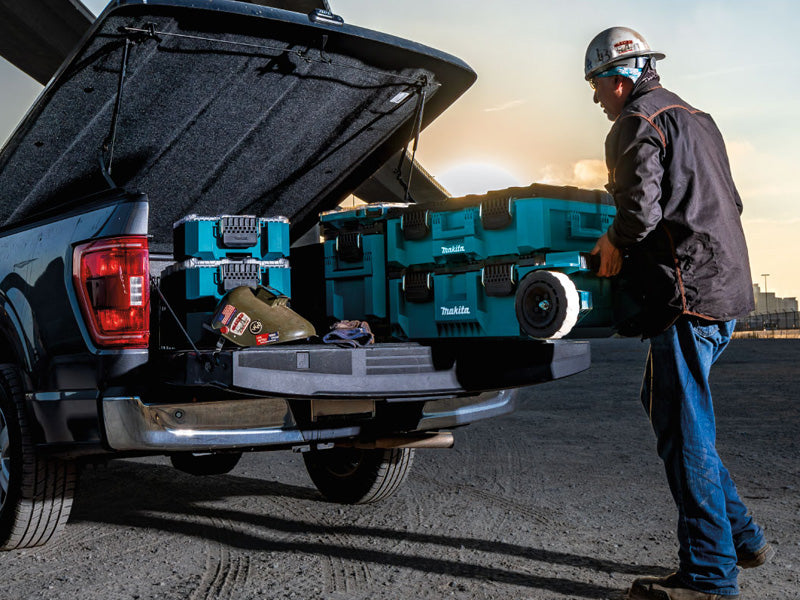 Man putting Makita MakTrak box into truck bed